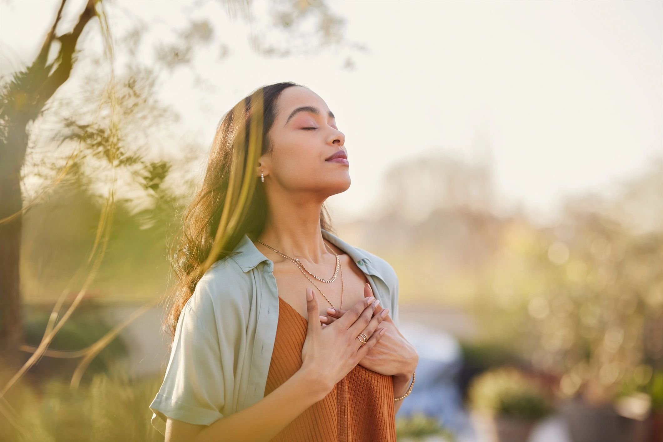 Woman practicing a calming breath outdoors at sunset