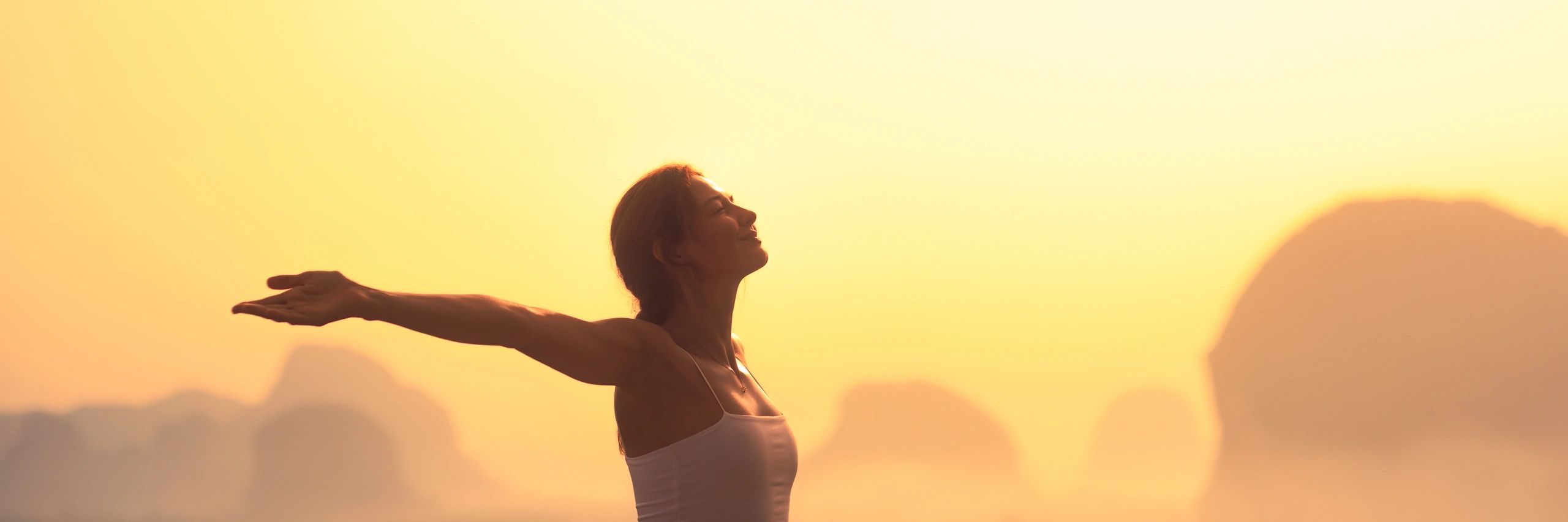 Woman breathing freely at sunrise in the mountains